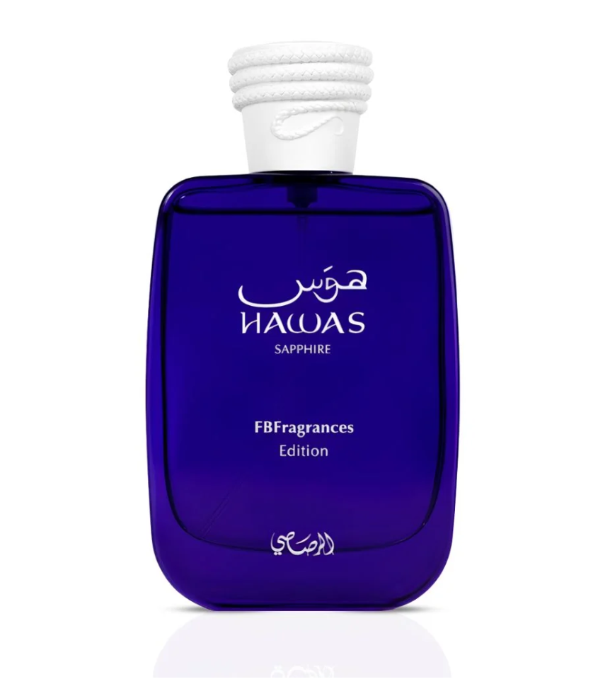 A cobalt blue glass fragrance bottle with a white textured cap, featuring white Arabic and English text that reads 'HUMAS SAPPHIRE' and 'FBFragrances Edition' on a clean white background.