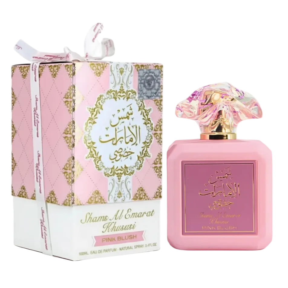 Pink blush perfume bottle and its decorative pink, white, and gold box on a clean white background. The bottle has a rounded pink body with a marbled pink and clear cap, and the box features gold ornamental detailing and Arabic text.