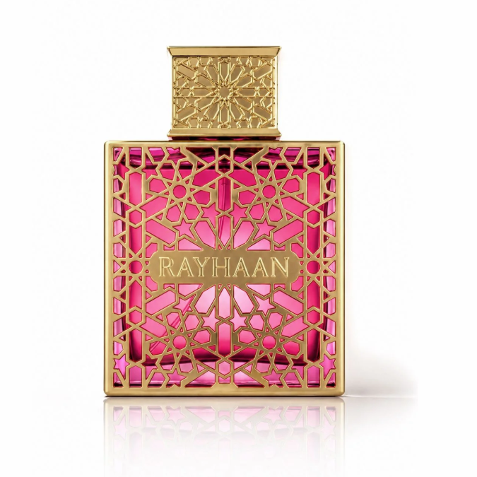 Rayhaan perfume bottle with a gold geometric metal frame and cap, showcasing a vibrant pink liquid inside, set against a clean white background with a soft reflection.