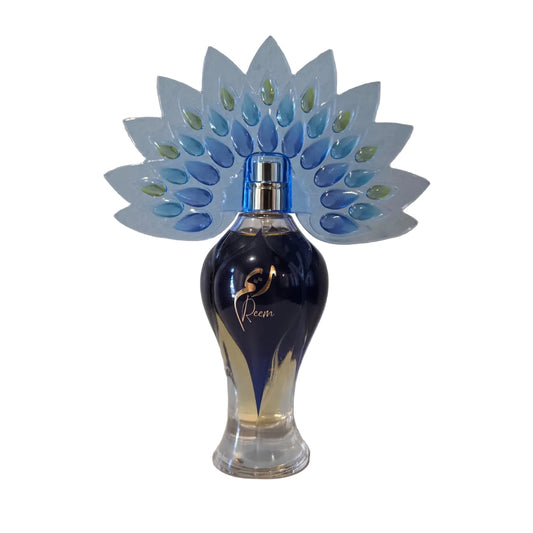 Blue perfume bottle with decorative peacock feather stand on a white surface